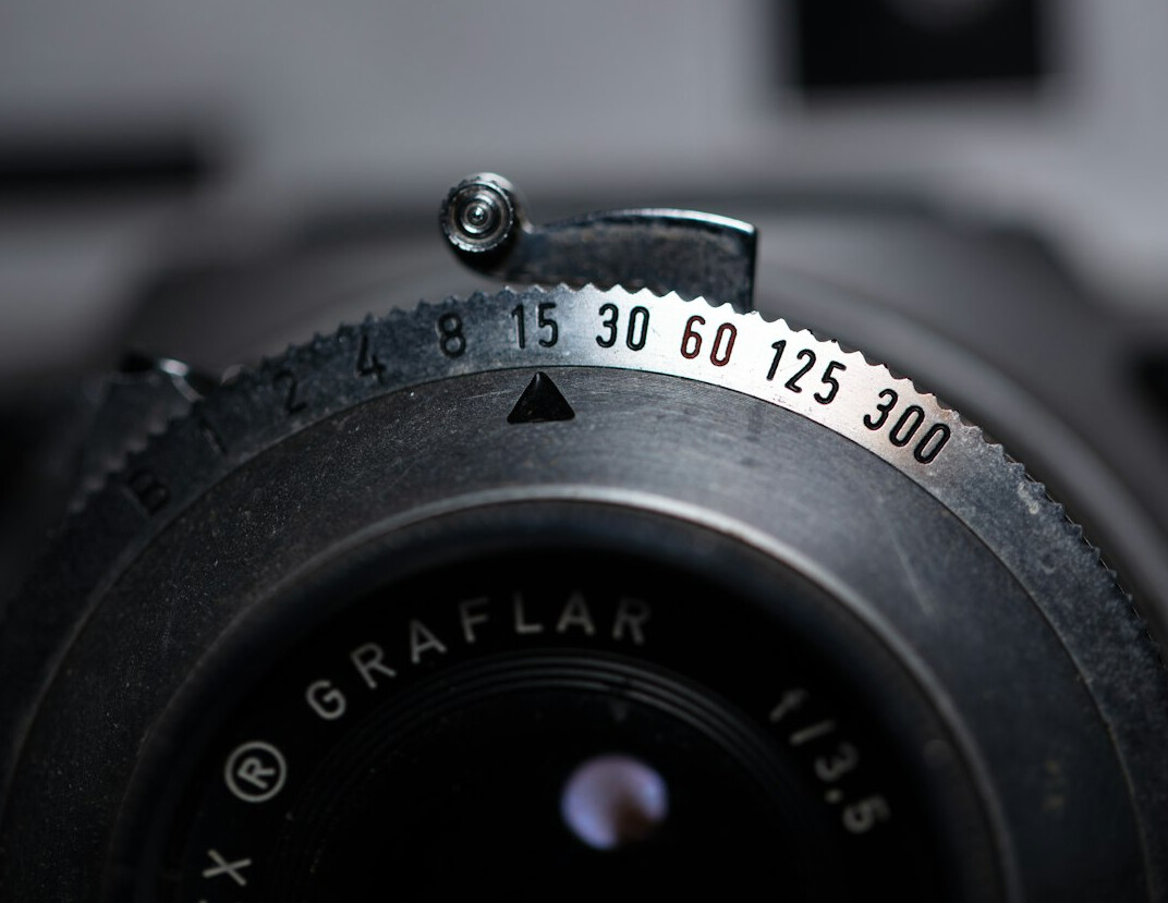 Close-up of camera gear, lenses and film rolls on a dark table