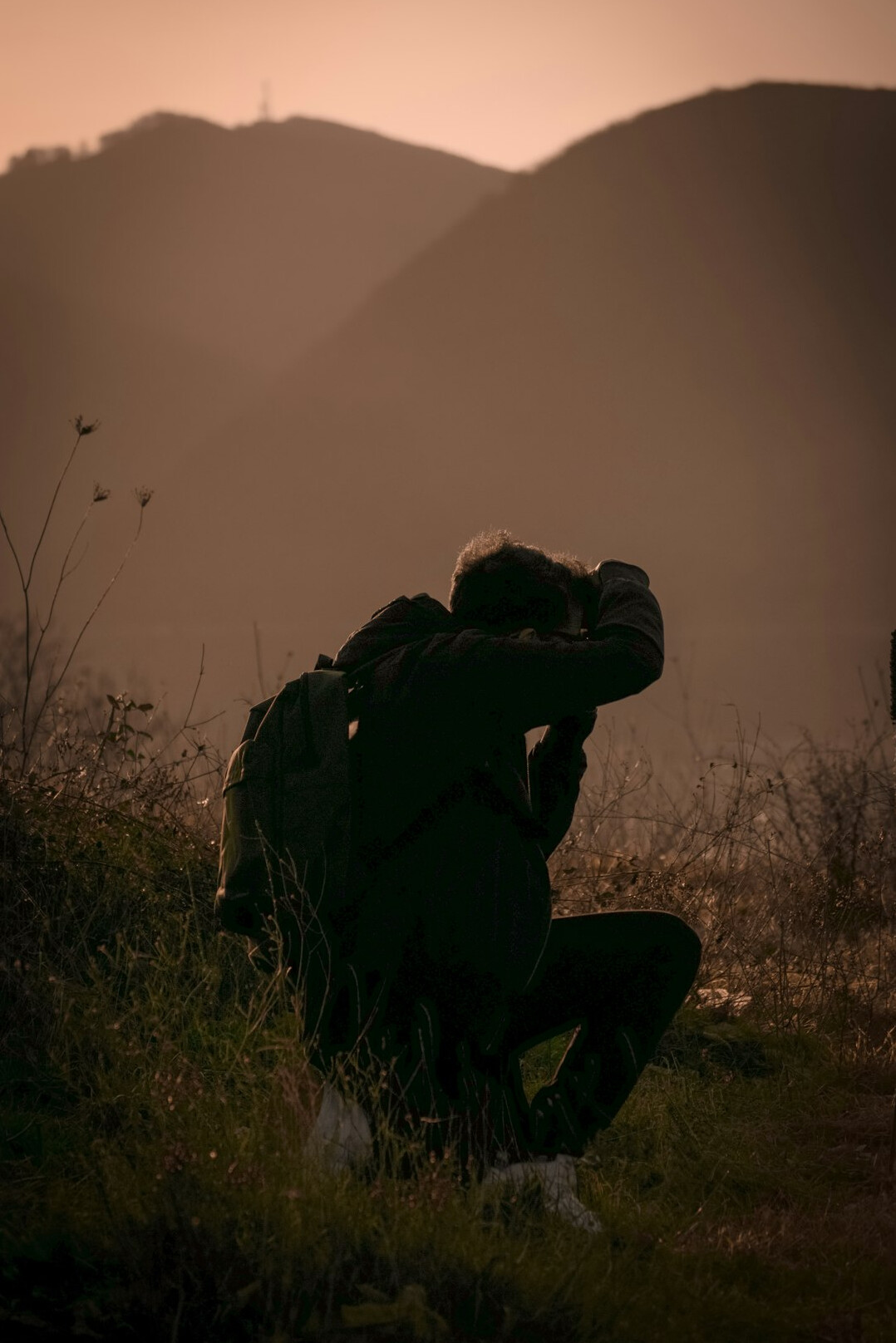 Photojournalist crouching to photograph a subject in the field